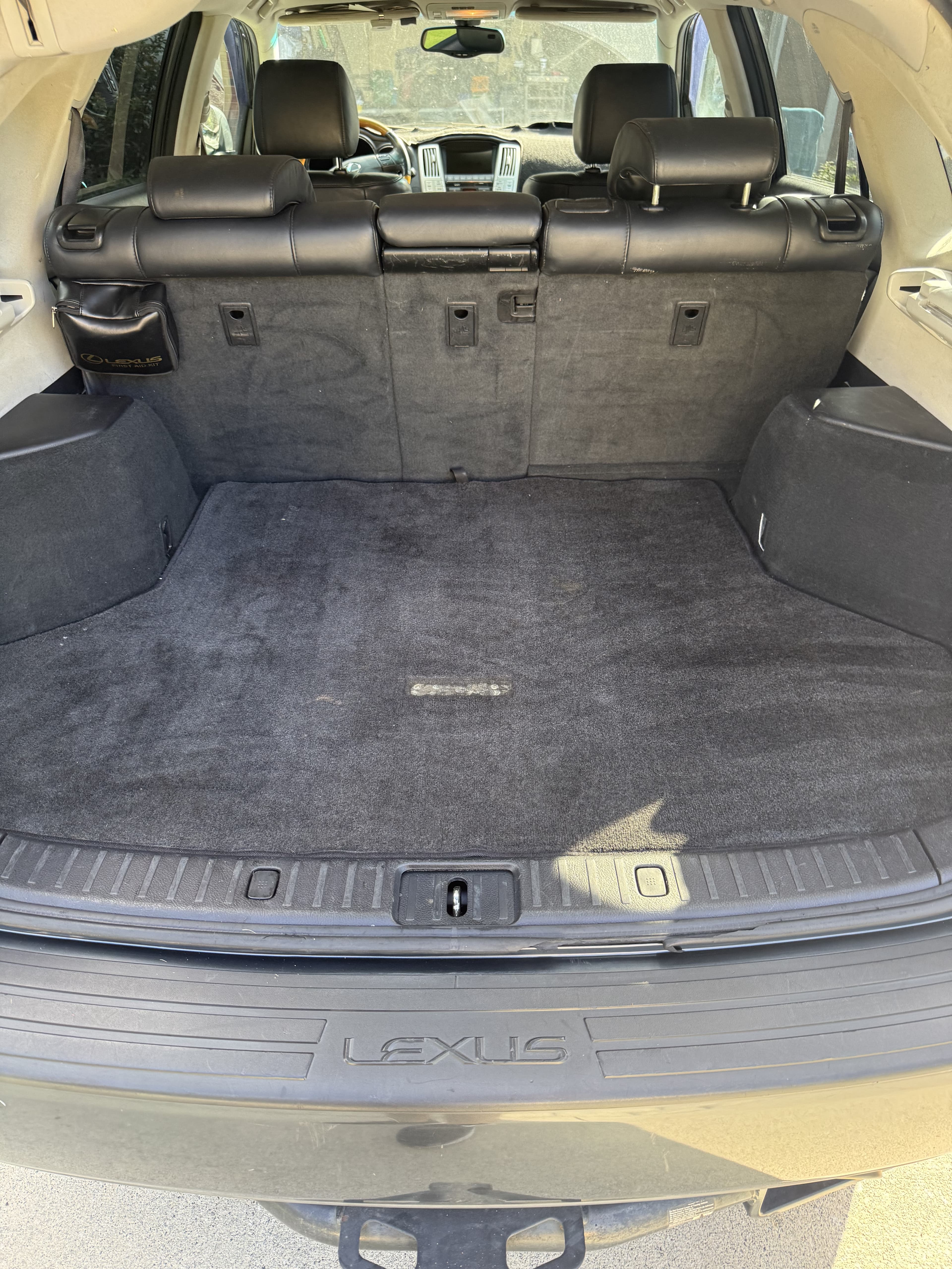 Empty black carpeted trunk of a Lexus SUV with rear leather seats and bumper.